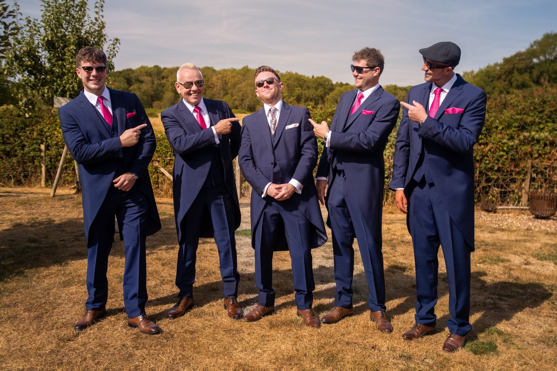 Five men in navy suits gathered outdoors before the wedding