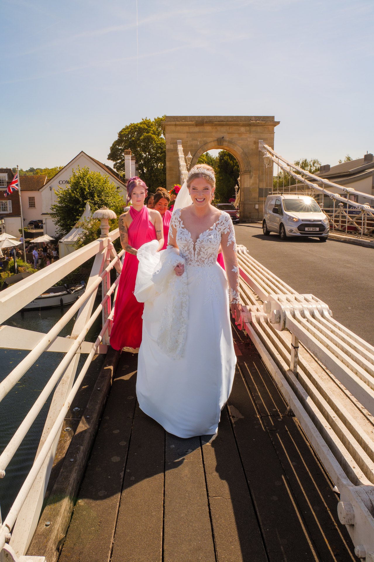 Lily walking across Marlow Bridge in her wedding dress